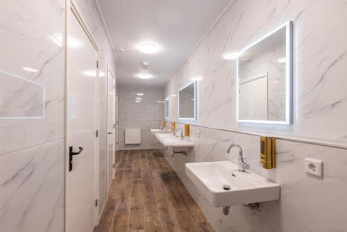Baño blanco con 2 lavabos y espejo en Hotel Leeuwerik, en Bad-Nieuweschans