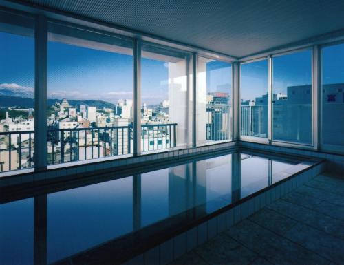 a swimming pool in a building with a view of the city at Himeji Green Hotel Tatemachi in Himeji