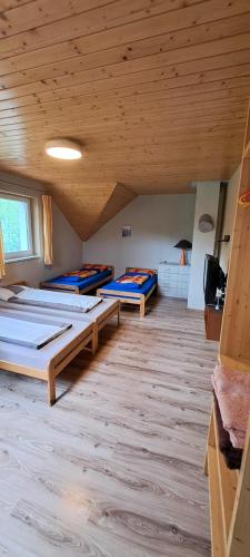 a room with four beds in it with a wooden ceiling at Ubytovanie U Huberta in Bešeňová