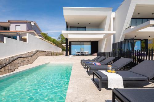 eine Villa mit einem Pool neben einem Haus in der Unterkunft Luxury Villa Ole with Pool in Kostrena