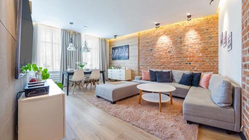 a living room with a couch and a brick wall at Apartamenty Sun & Snow Karlikowo in Sopot