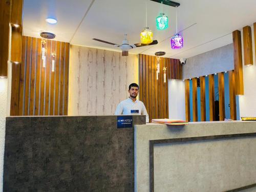 un hombre parado en un mostrador en una oficina en Hotel Stay Well Pithampur en Akolia