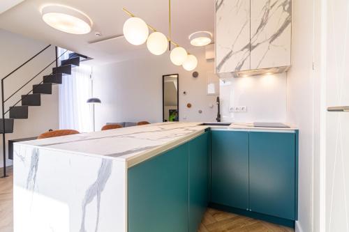 a kitchen with blue cabinets and a staircase at Green Shine Apartment, By Cohost in Palanga
