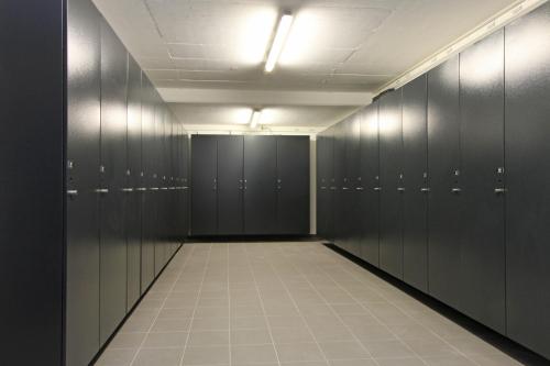 an empty locker room with black lockers and a corridor at AvenidA Mountain Lodges Kaprun in Kaprun