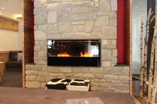 a living room with a stone wall with a fireplace at AvenidA Mountain Lodges Kaprun in Kaprun