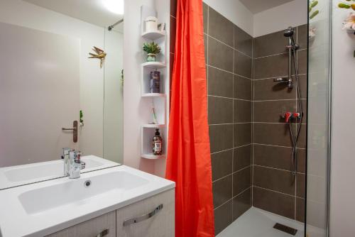 La salle de bains est pourvue d'un lavabo et d'une douche avec un rideau de douche orange. dans l'établissement Bibifoc Baie - au coeur de la Baie de la Somme, à Saint-Valery-sur-Somme