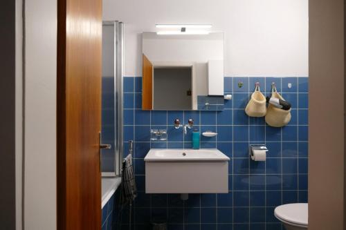 サンモリッツにあるAllod Bad 109の青いタイル張りのバスルーム(シンク、鏡付)