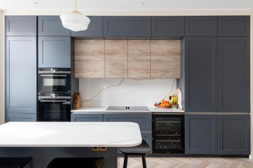een keuken met blauwe kasten en een witte tafel bij ALTIDO Spectacular house with private garden in Londen