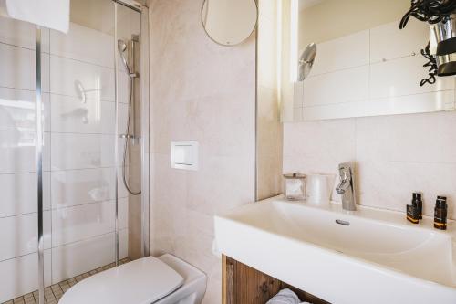 a bathroom with a sink and a shower and a toilet at AvenidA Mountain Lodges Kaprun in Kaprun