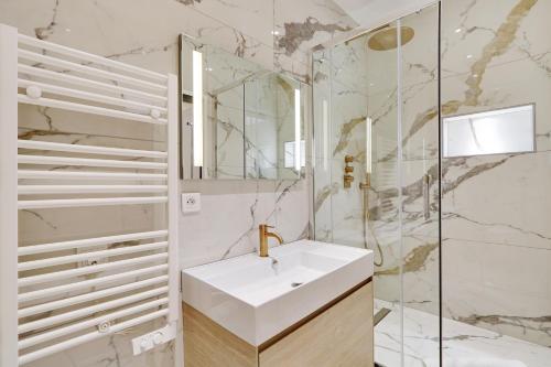 une salle de bain blanche avec un lavabo et un miroir dans l'établissement Pick A Flat's Apartment in Parc Monceau - Boulevard de Courcelles, à Paris
