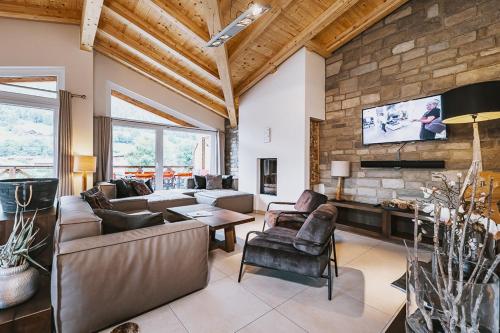 a living room with a couch and a tv at AvenidA Mountain Lodges Kaprun in Kaprun