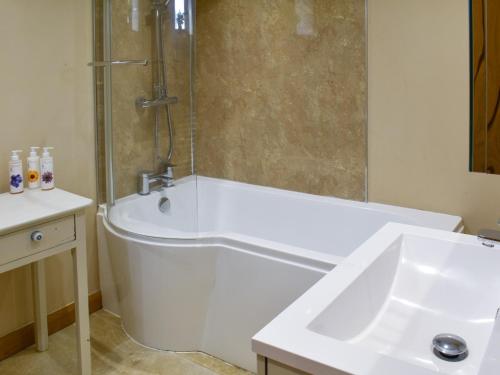 a bathroom with a shower and a tub and a sink at The Cow Shed in Hooe