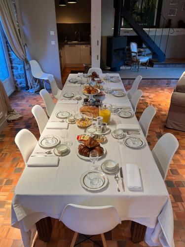 uma longa mesa branca com pratos de comida em Manoir de la Prise Tarot em Bagnoles de l'Orne