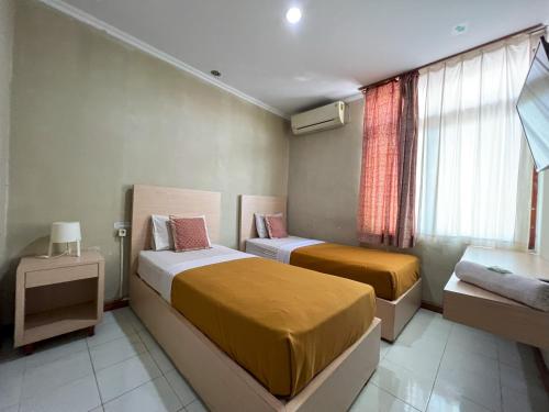 - une chambre avec 2 lits et une fenêtre dans l'établissement Hotel Winotosastro by Athelu, à Timuran