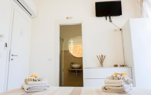 sypialnia z białymi ścianami i łóżkiem z ręcznikami w obiekcie In Centro rooms w mieście Castellabate