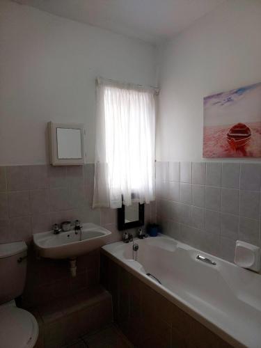 a bathroom with a tub and a sink and a toilet at OCEAN VIEW, DOLPHIN BAY 19 ASTON BAY in Jeffreys Bay