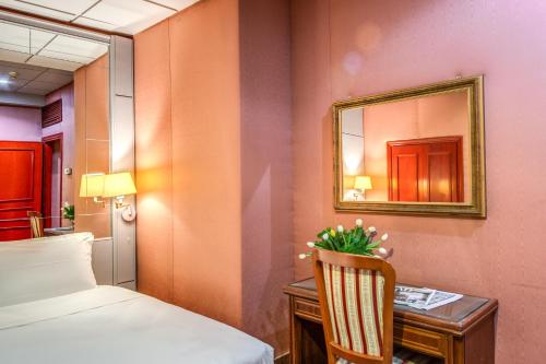 a room with a bed and a desk and a mirror at Castro Pretorio 64 Easy Rooms in Rome