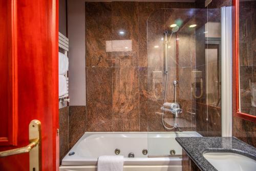a bathroom with a tub and a glass shower at Castro Pretorio 64 Easy Rooms in Rome
