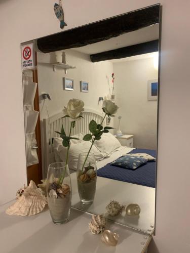 a mirror on a table with two plants in a bedroom at BeB CASABARBARA a due passi dal mare in Lerici