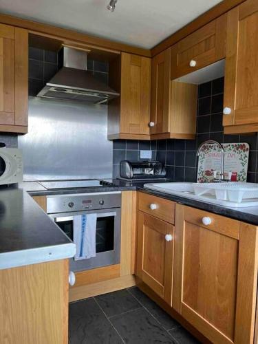 a kitchen with wooden cabinets and a stove top oven at Gors Eilian in Amlwch