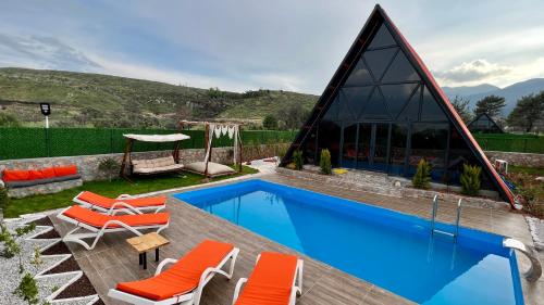 una piscina con sedie arancioni e una casa di villa hidden paradise garden a Fethiye