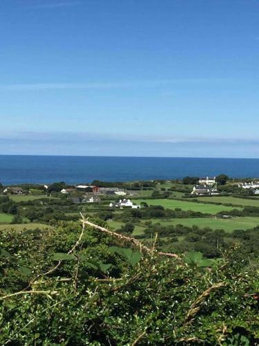a view of a field with the ocean in the background at Gors Eilian in Amlwch