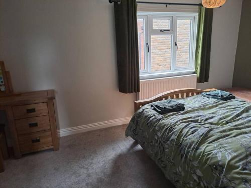 a bedroom with a bed and a dresser and a window at Cosy cottage near Alton Towers in Rocester
