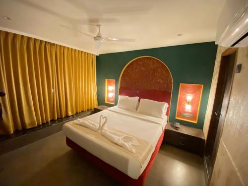 Gulf Hotel Mumbai- The Boutique Hotel Colaba Mumbai في مومباي: غرفة نوم بسرير كبير وبجدار احمر واخضر