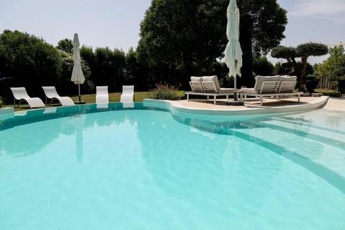 une grande piscine avec chaises et parasols dans l'établissement Superbe Mas contemporain au pied du Luberon, à Cheval-Blanc