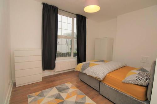 Schlafzimmer mit einem Bett und einem Fenster in der Unterkunft Ideal 2 Bed Flat close to City in London