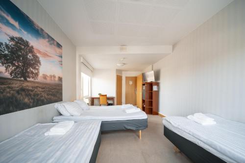 a room with two beds and a painting on the wall at Hotelli Uninen Kotka in Kotka