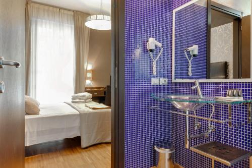 La salle de bains est pourvue d'un mur carrelé bleu et d'un lavabo. dans l'établissement Atmosfere Milano Marittima, à Milano Marittima
