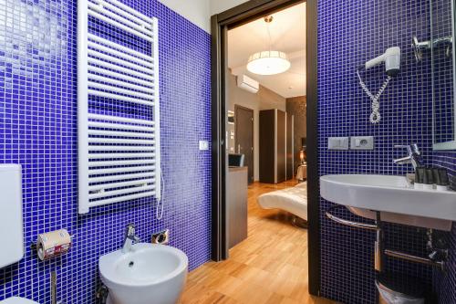 a blue tiled bathroom with a sink and a mirror at Atmosfere Milano Marittima in Milano Marittima