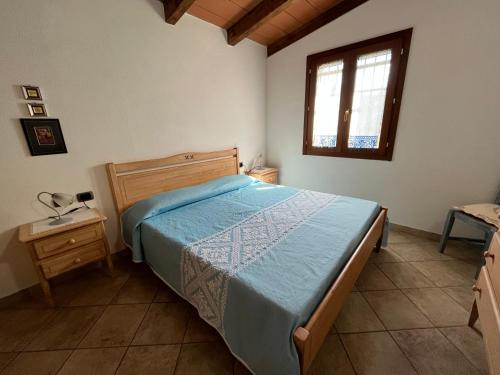a bedroom with a bed with a blue comforter and a window at Casa Costera in Orosei
