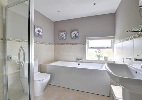 a bathroom with a tub and a toilet and a sink at Rockley Cottage in Egton
