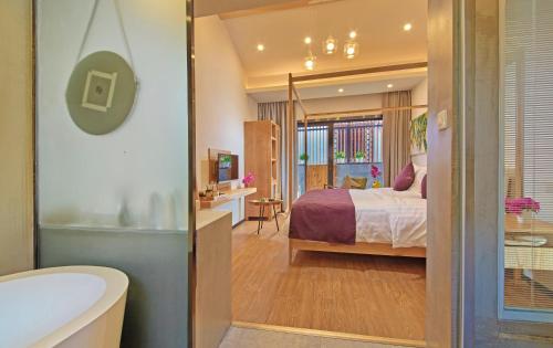 WuZhen Dream Hotel في Tongxiang: غرفة نوم بسرير وحمام مع حوض استحمام