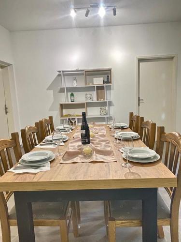 - une table en bois avec des chaises et des assiettes ainsi qu'une bouteille de vin dans l'établissement Two Stars Apartment, à Podstrana