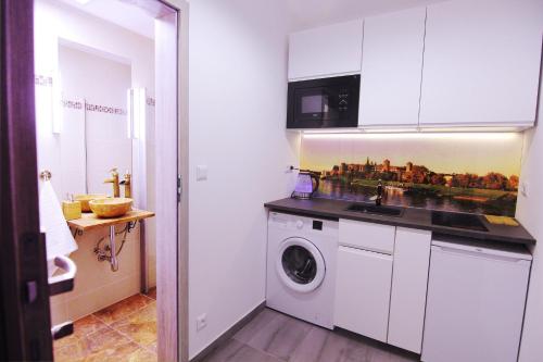 a kitchen with a washing machine in a white kitchen at Cozy studio on Wielopole street. in Krakow