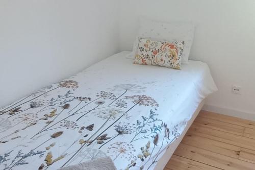 a bed with a floral bedspread and a pillow on it at Moradia na Serra in Alcanede