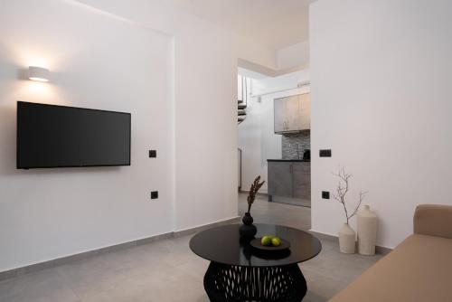 sala de estar con TV en una pared blanca en AKRI Suites Vourvoulos, en Vourvoúlos