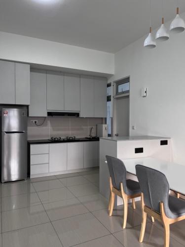 cocina con armarios blancos, mesa y sillas en Duck Duck House 3BR 7-11 PAX, en Johor Bahru