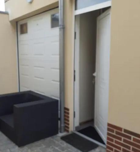a garage with two garage doors and a black couch at Studio chaleureux Beauvais-centre, gare et proche Aéroport in Beauvais