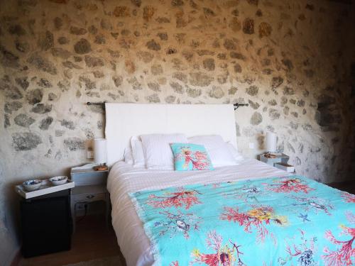 a bedroom with a bed with a blue comforter at Le Cabanon de Gourdon bergerie rénové en pierre vue mer in Gourdon