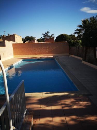 une piscine avec une clôture et de l'eau bleue dans l'établissement Maisonnette 4 pers rez de jardin avec terrasse, au Cap d'Agde