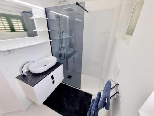 uma casa de banho branca com um lavatório e um chuveiro em Apartments Eis em Baška