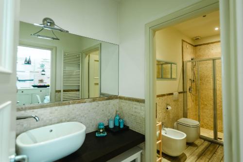 bagno con lavandino, servizi igienici e specchio di TERESITA WELLNESS CLUB a Viareggio