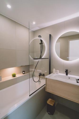 une salle de bain avec un lavabo, une douche et un miroir dans l'établissement Noirmoutier Le Grand Large, à LʼHerbaudière