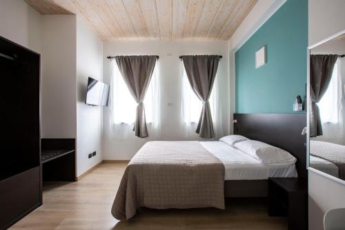 una camera con un letto e due finestre di Il B&B di Piazza Motta ad Albese Con Cassano