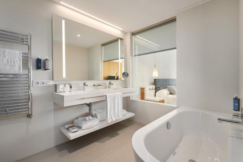 a white bathroom with a tub and a sink at Hipotels Playa de Palma Palace&Spa in Playa de Palma