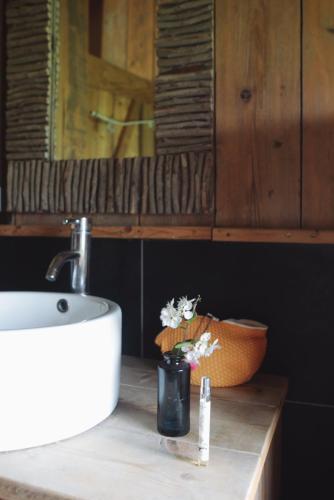 La salle de bains est pourvue d'un lavabo et d'un vase de fleurs. dans l'établissement Tentes Safari aux Gîtes de Cormenin, à Saint-Hilaire-sur-Puiseaux